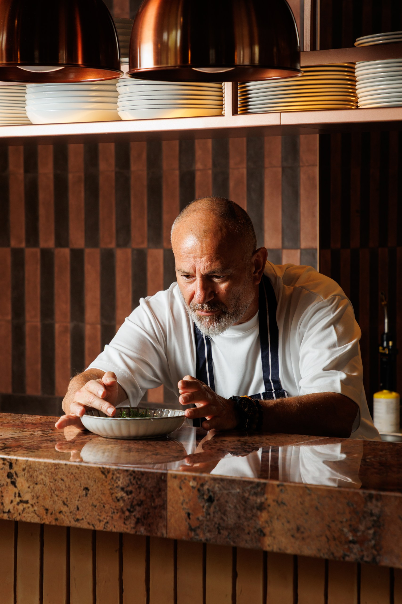 Chef plating a dish with fresh herbs at the pass